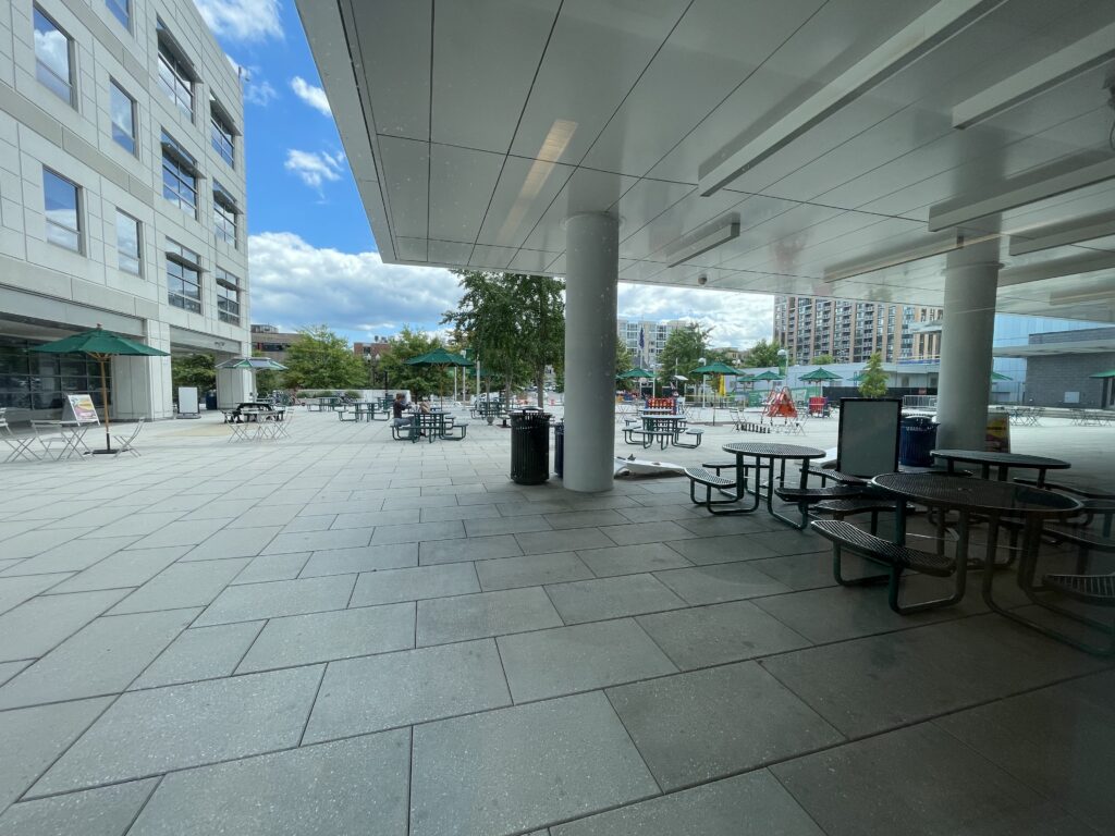 large open plaza, partially roofed, with picnic tables and umbrellas